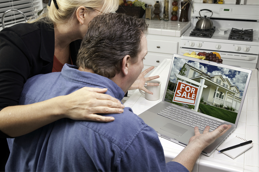 Couple In Kitchen Using Laptop to Research Real Estate. Screen can be easily used for your own message or picture. Pi...